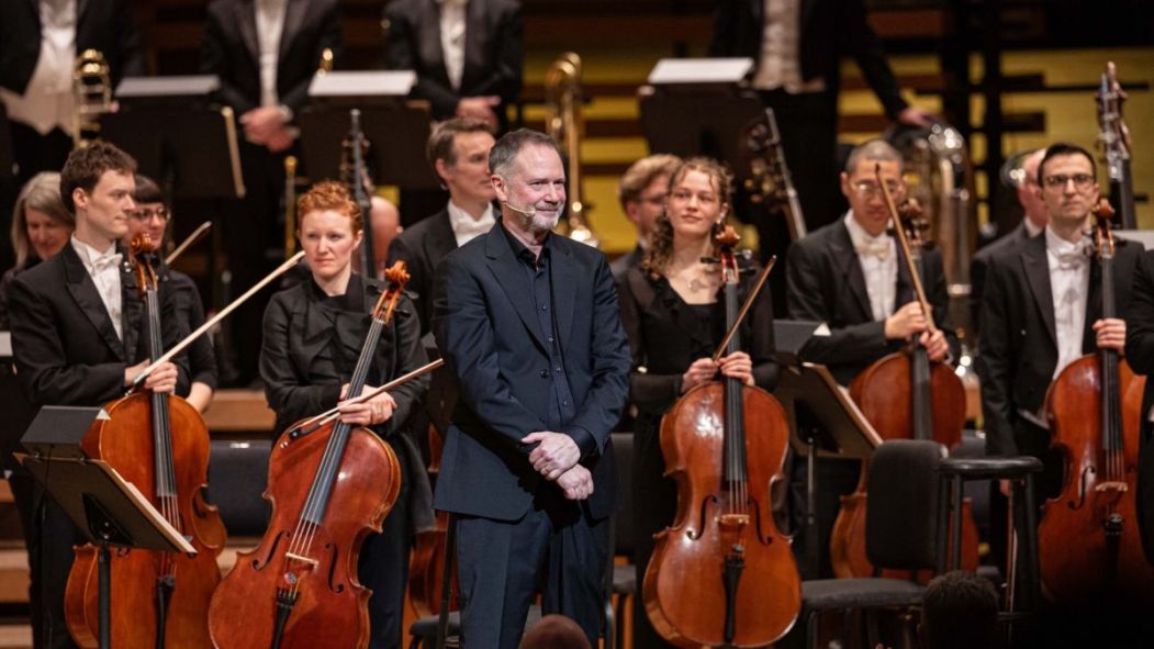 François Pérusse se tient devant les musiciens de l'Orchestre symphonique de Montréal pendant le spectacle Pérusse symphonique.