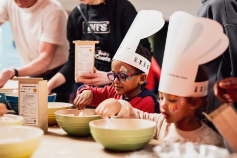 Des enfants portent un chapeau de cuisinier et apprennent la cuisine.