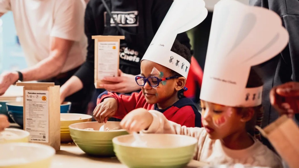 Des enfants portent un chapeau de cuisinier et apprennent la cuisine.