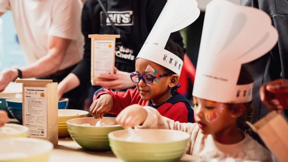 Des enfants portent un chapeau de cuisinier et apprennent la cuisine.