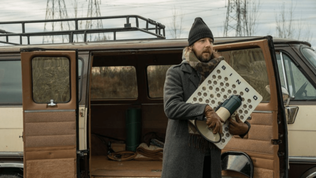 Un homme tient plusieurs objets en sortant d'une fourgonette. Prise d'image du film Kairos.