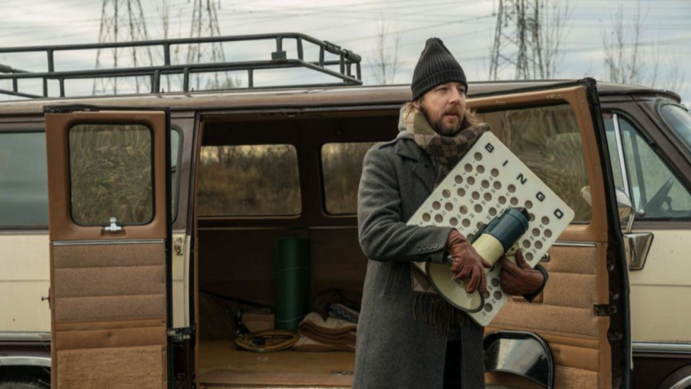 Un homme tient plusieurs objets en sortant d'une fourgonette. Prise d'image du film Kairos.