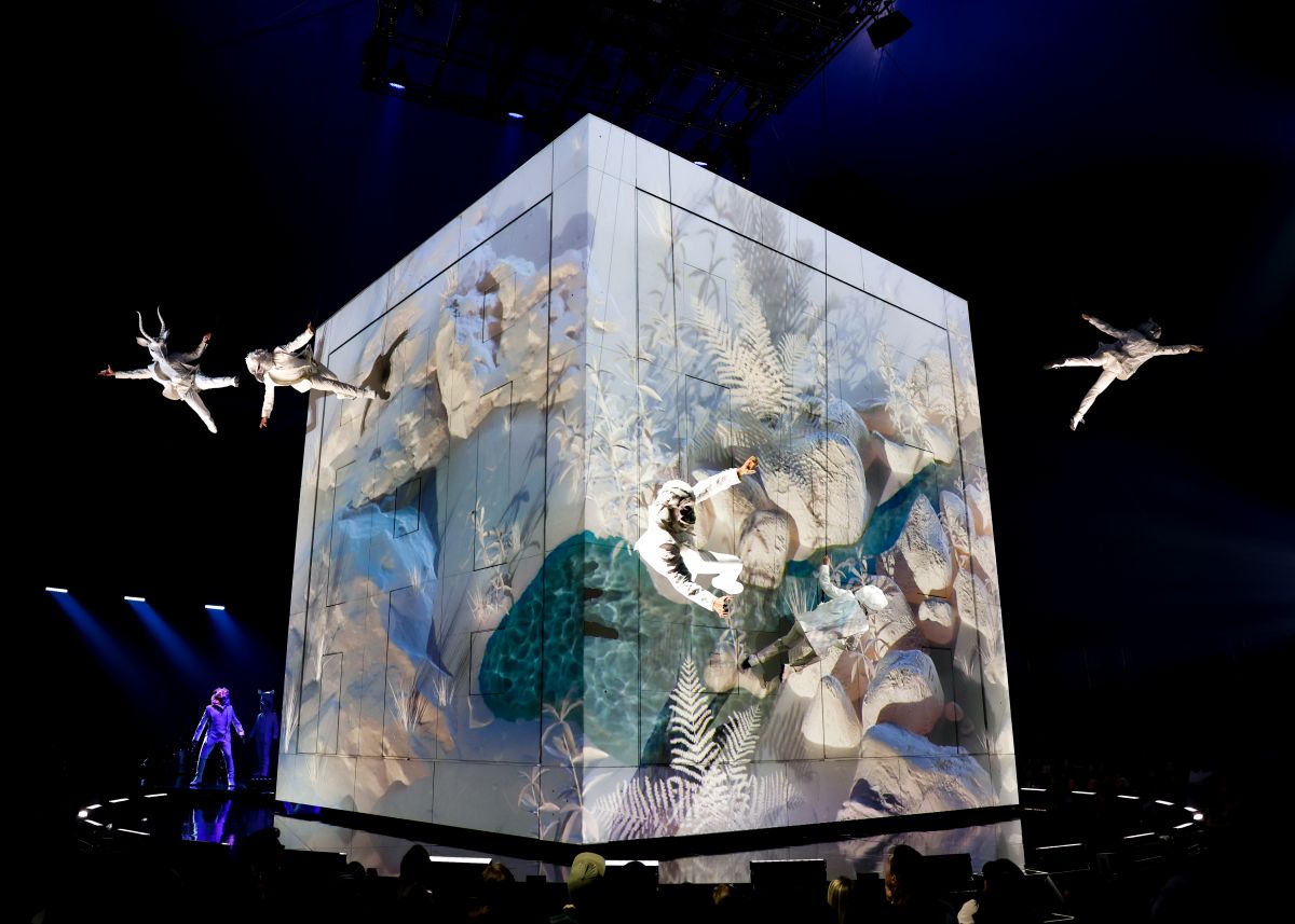Des acrobates du Cirque du Soleil survolent un énorme cube peint.