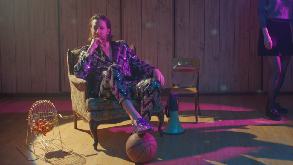 Image fixe du film Kaïros montrant un personnage assis sur une chaise en habit disco.