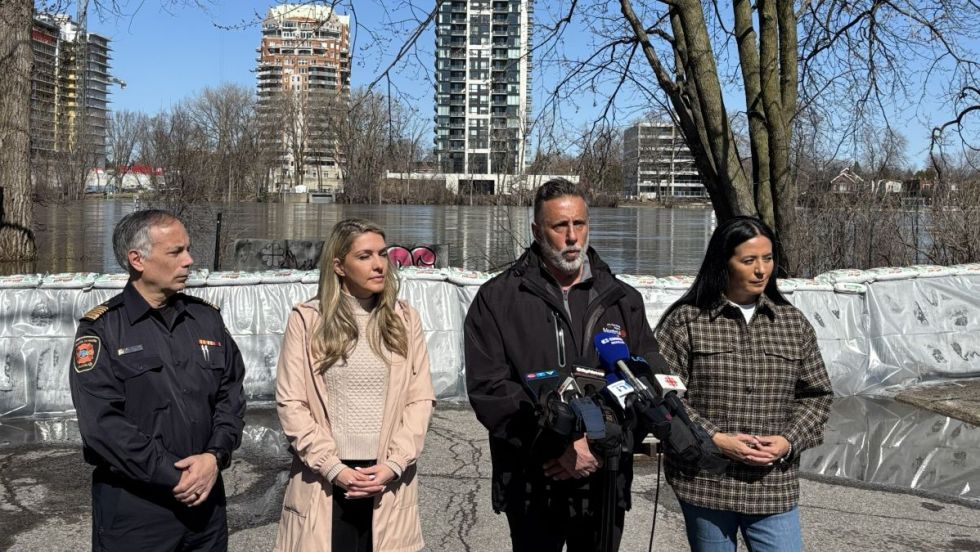 Richard Liebmann, Effie Giannou, Jim Beis et Soraya Martinez Ferrada devant une digue installée le long de la rivière des Prairies, dans Ahuntsic-Cartierville.