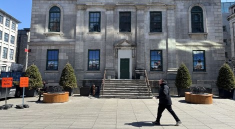 Un homme marche devant la Place Royale, dans le Vieux-Montréal.