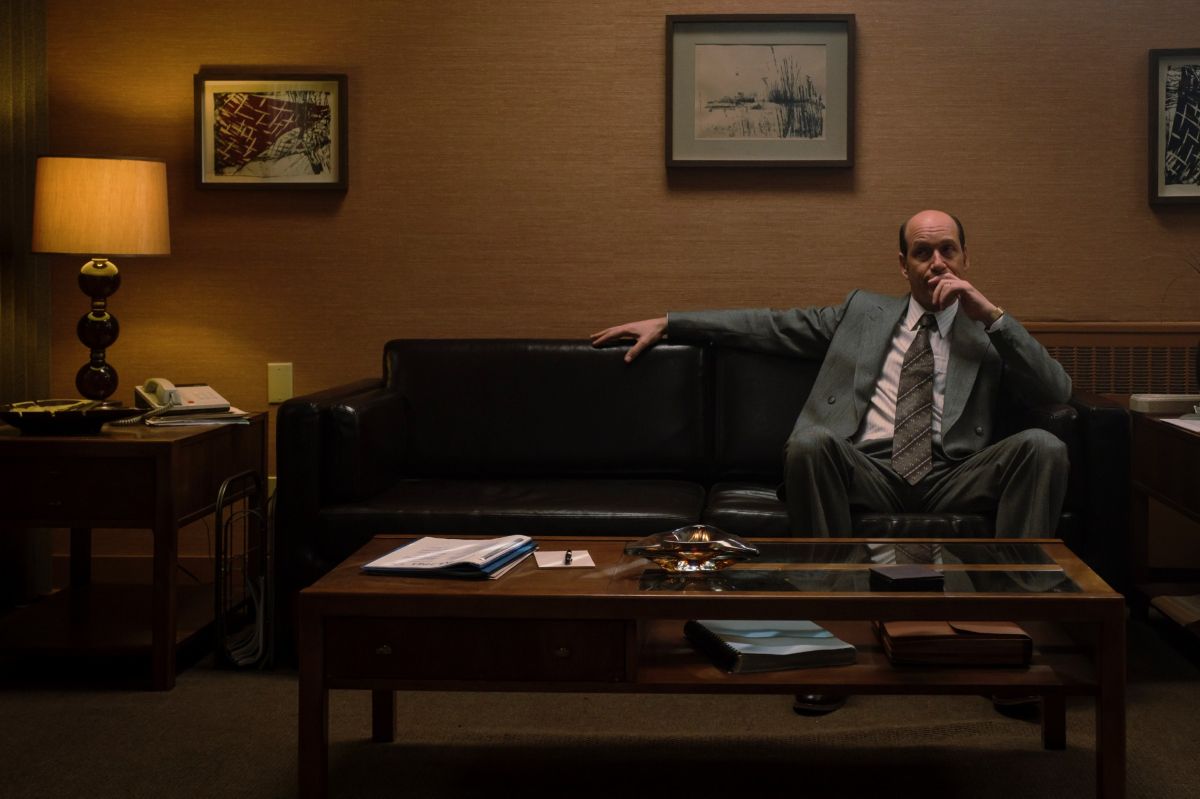 Le personnage de Martin Matte dans Vitrerie Joyal, André Joyal, est assis seul sur un divan.