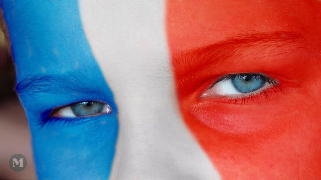 Un visage maquillé aux couleurs du drapeau tricolore de la France, avec gros plan sur les yeux.