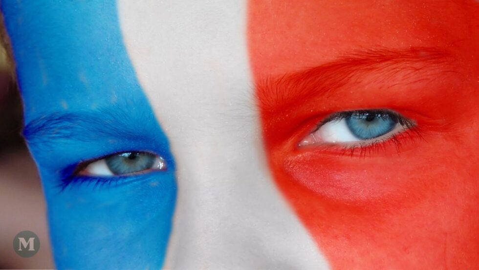 Un visage maquillé aux couleurs du drapeau tricolore de la France, avec gros plan sur les yeux.