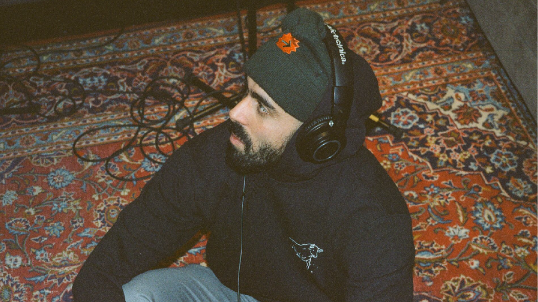 L'humoriste Adib Alkhalidey assis sur un tapis avec un casque d'écoute sur la tête.