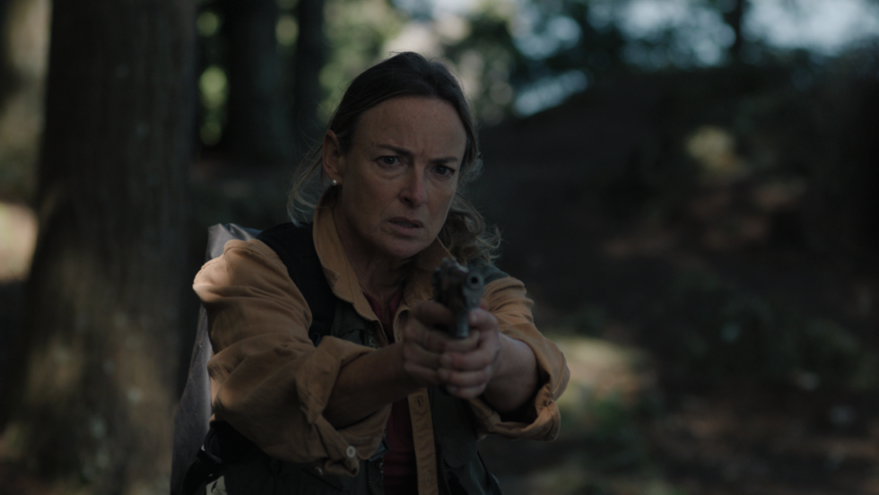 Pascale Bussières tient une arme à feu dans une scène du film Sans Témoins (Someone's Daughter).