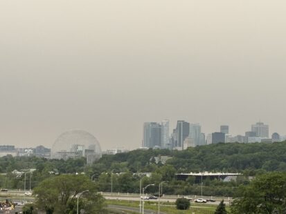 Vue du skyline de Montréal à partir de Longueuil, alors que le ciel est ennuagé et l'air est jaunis par les feux de forêt de l'Ontario.