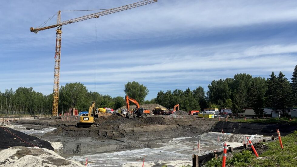 Une grue et des pelles mécaniques s'affairent sur un chantier de construction de logements dans Pointe-aux-Trembles.