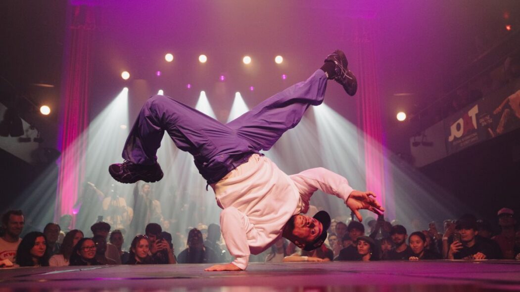 Un homme se tient sur une main pendant une prestation de break dance lors du festival JOAT.