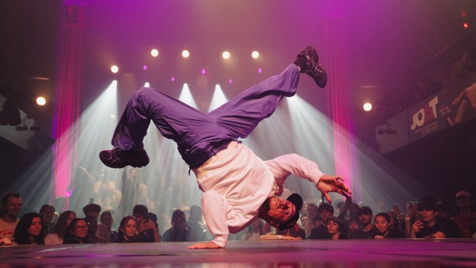 Un homme se tient sur une main pendant une prestation de break dance lors du festival JOAT.