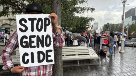 Un homme tient une affiche demandant la fin du génocide lors d'une manifestation pro-palestinienne à Montréal.