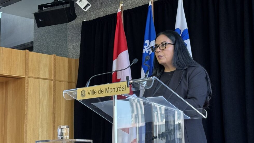 Soraya Martinez Ferrada devant des drapeaux de la Ville de Montréal, du Québec et du Canada.