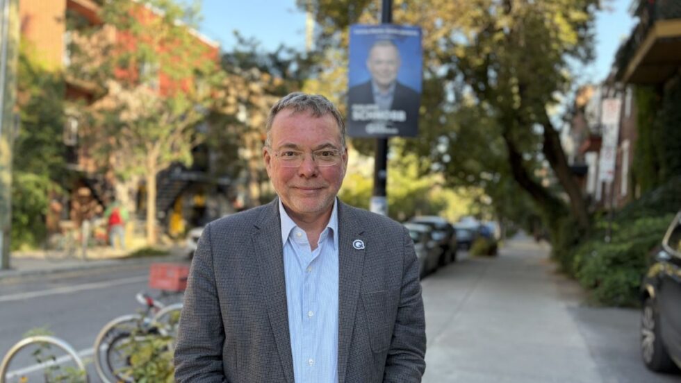 Philippe Schnobb devant son affiche de candidat, sur une rue du Plateau.
