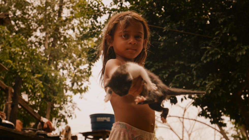 Un enfant tient un chat en Amazonie dans une scène du docufilm L'Ère de feu.